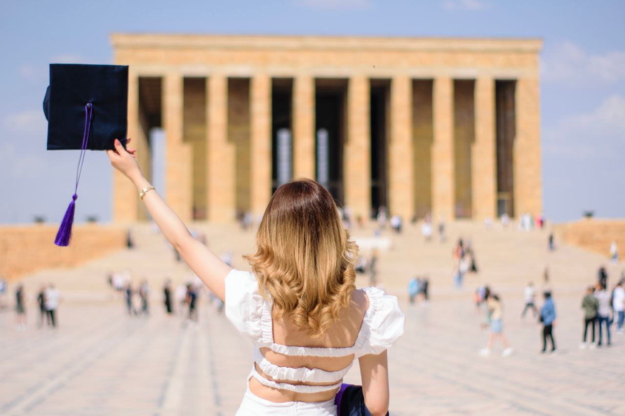 Young woman celebrates graduation in front of Anıtkabir, a significant Turkish landmark.