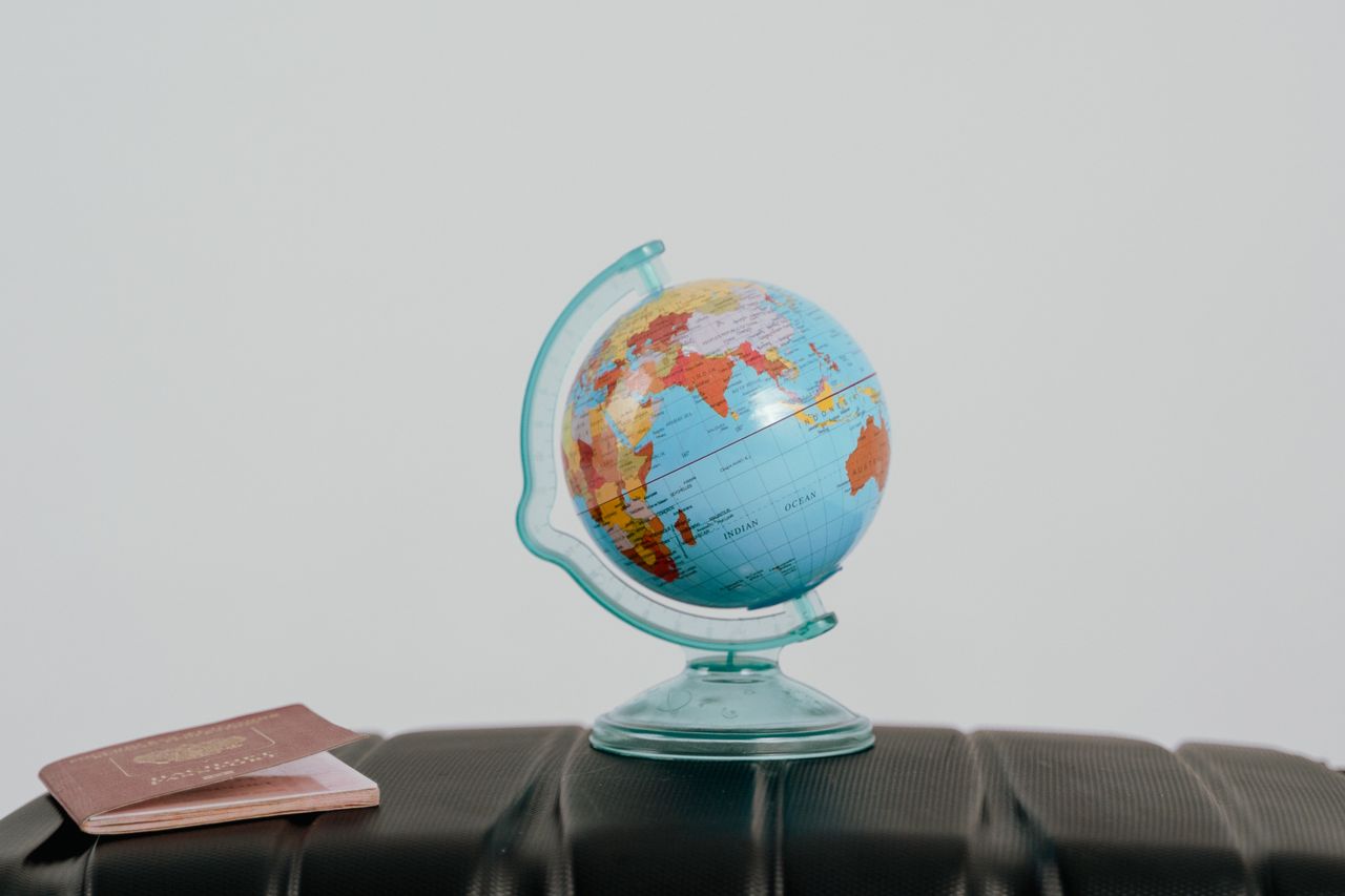 Mastering the First Impression: Your intriguing post title goes here A globe and passport on a suitcase, symbolizing travel planning and wanderlust.